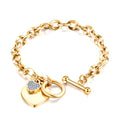 Gold chain bracelet with heart-shaped charm and lock on a white background